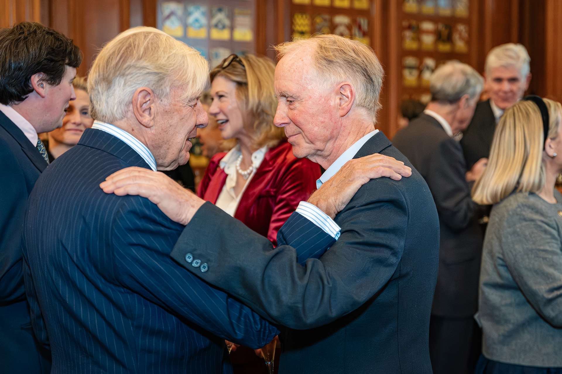 Photograph of two older gentlemen with a hand on each other's shoulder, reuniting from an old friendship. Taken at the Georgian Group Architecture Awards night in London, UK, by Marc James.