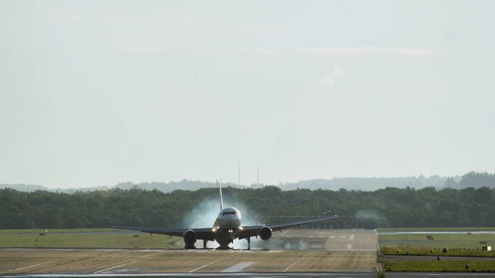 Middle distance shot of twin engine commercial airplane landing at the airport with strong crosswind. Early morning time