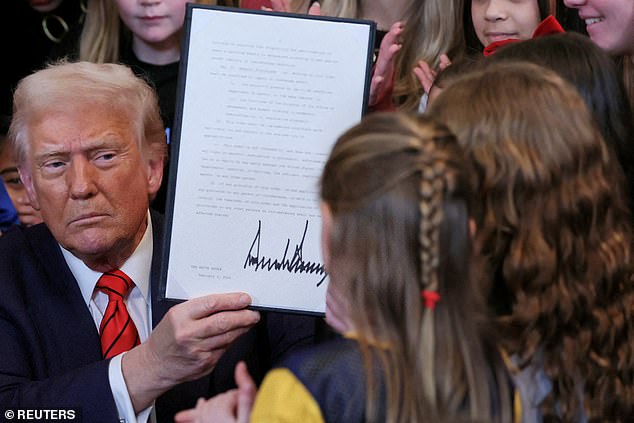 President Donald Trump holds up a signed executive order banning transgender girls and women from participating in women's sports