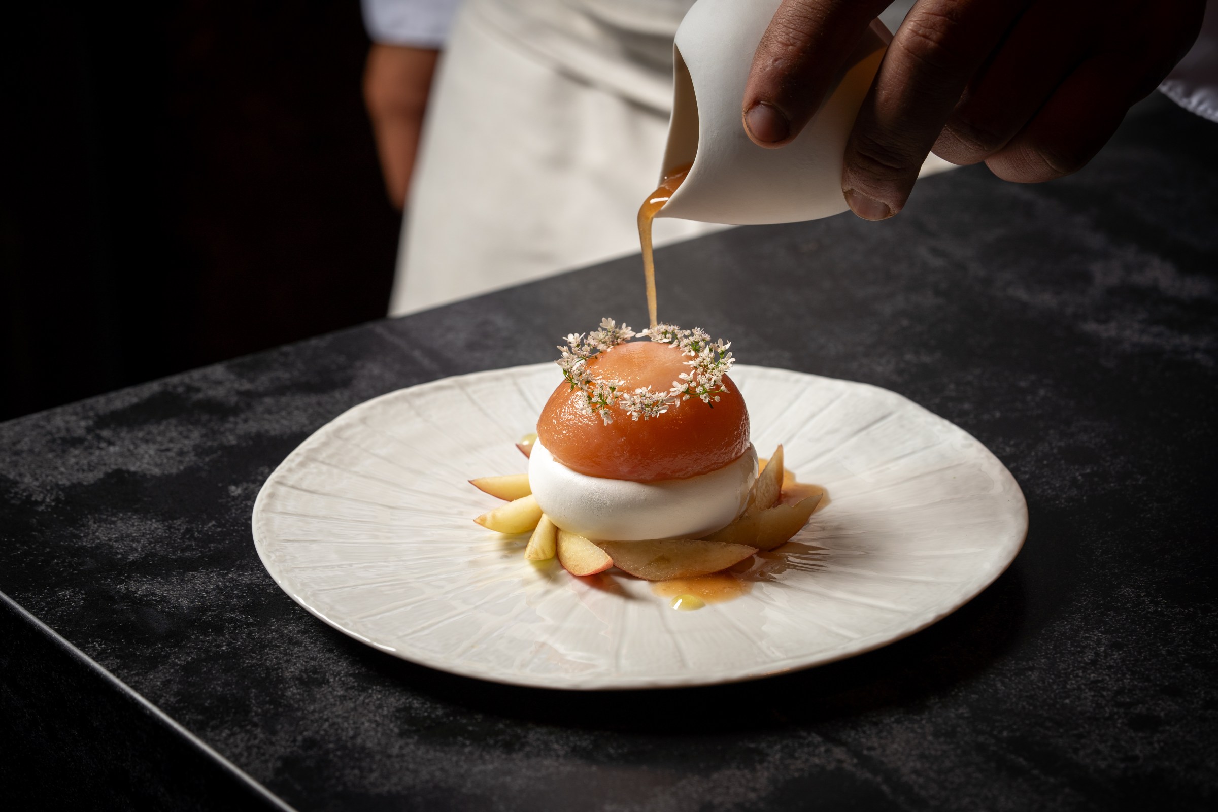 A delicate dessert course of fruit and cream topped with delicate flowers.