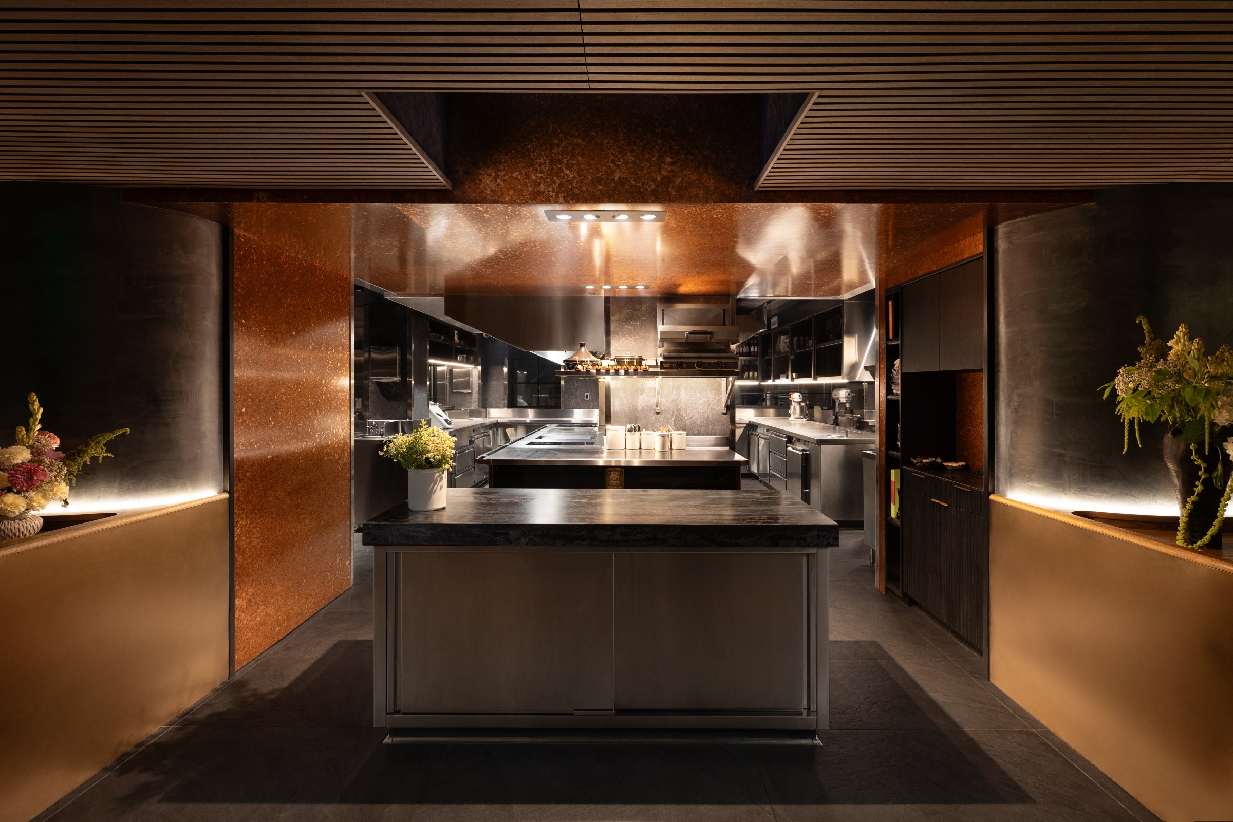 An open kitchen with dark countertops and brown walls.