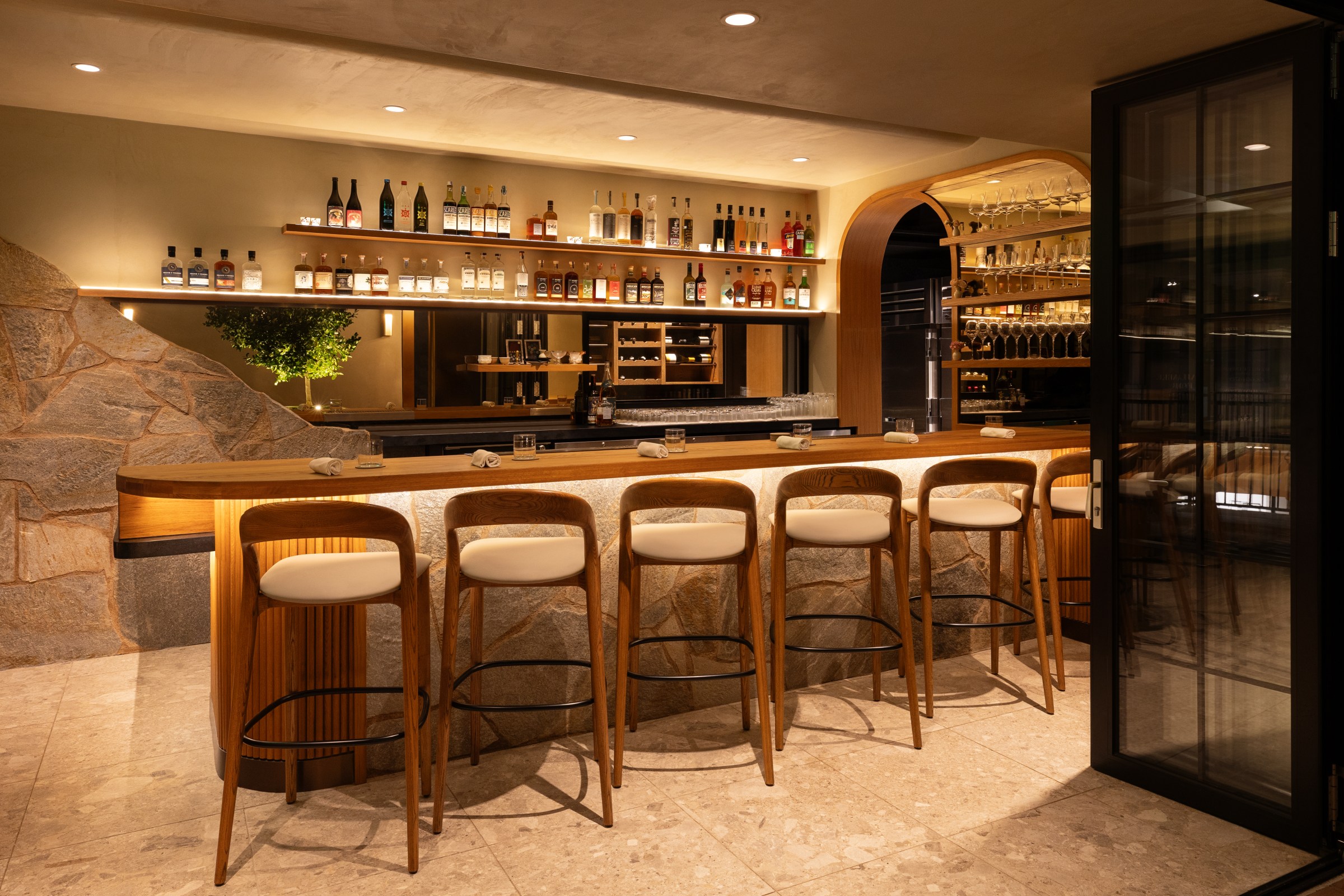An elongated oak bar atop a sculpted quartzite rock. 