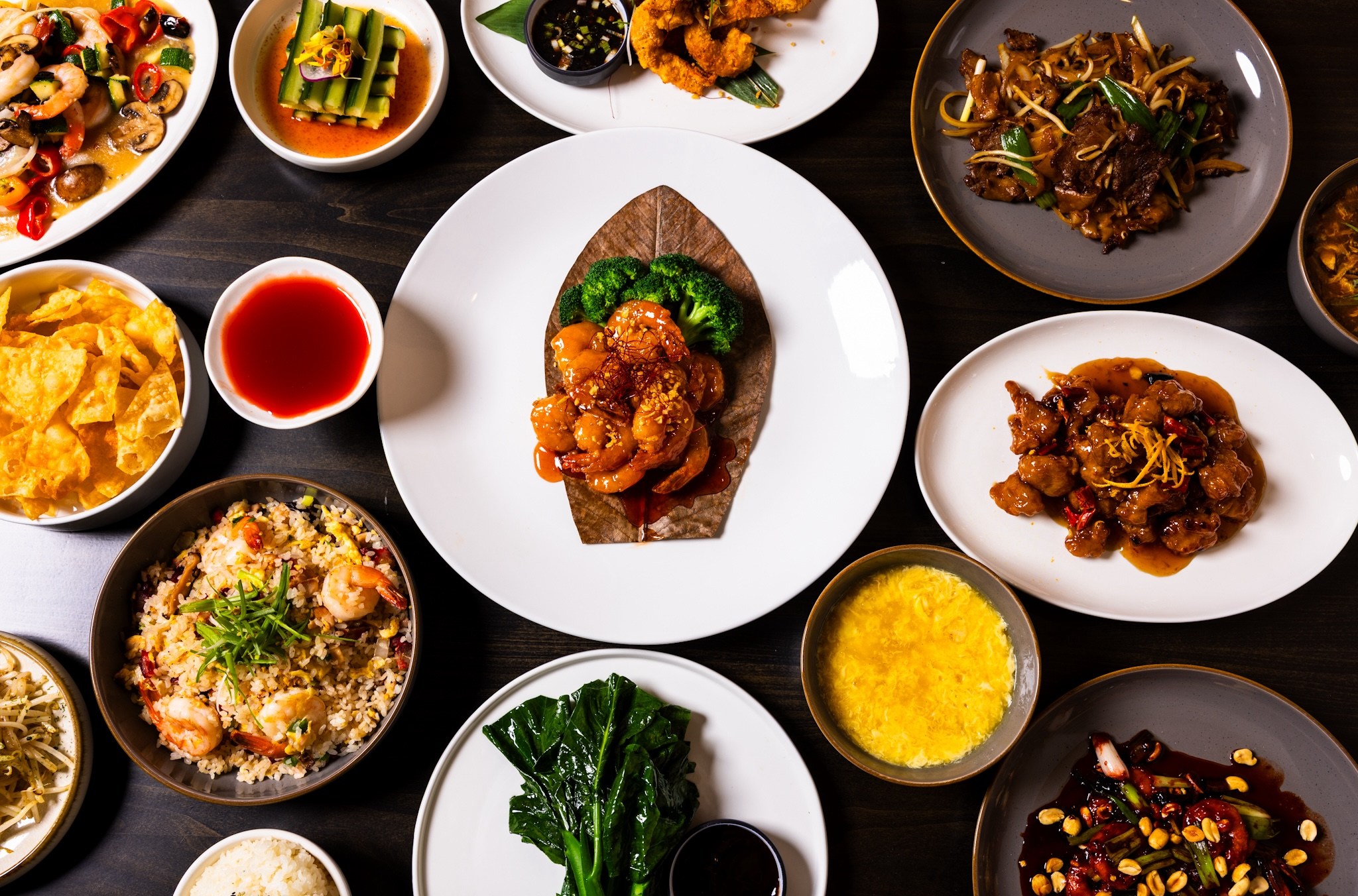 Spread of Chinese diasporic dishes on a wooden table.