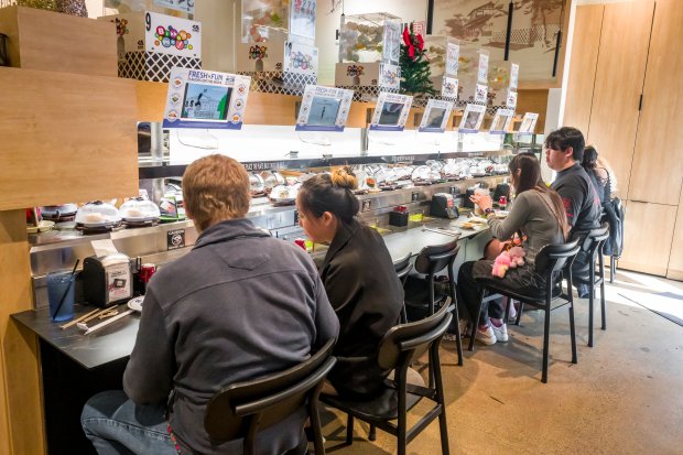 Customers dine as food items pass by on a conveyor...