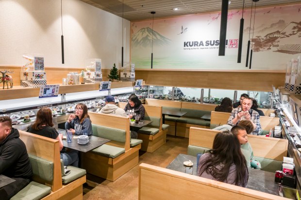 Customers dine inside Kura Revolving Sushi Bar at the Brea...