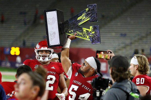 Fresno State offensive lineman Bula Schmidt holds up the Valley trophy after defeating San Jose State during the second half of an NCAA college football game in Fresno, Calif., Saturday, Oct. 15, 2022. (AP Photo/Gary Kazanjian)