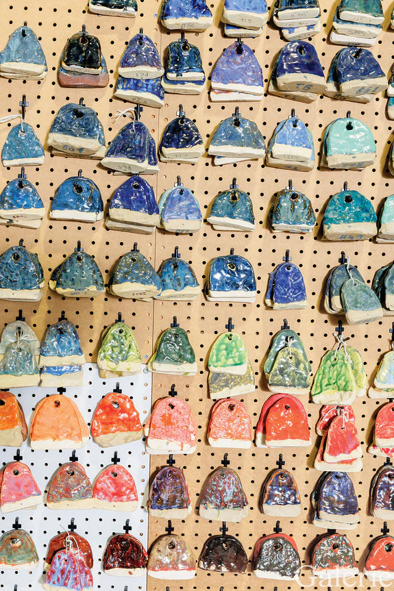 Colorful ceramic wall hooks displayed on a pegboard in various shapes and shades including blue, green, and orange.