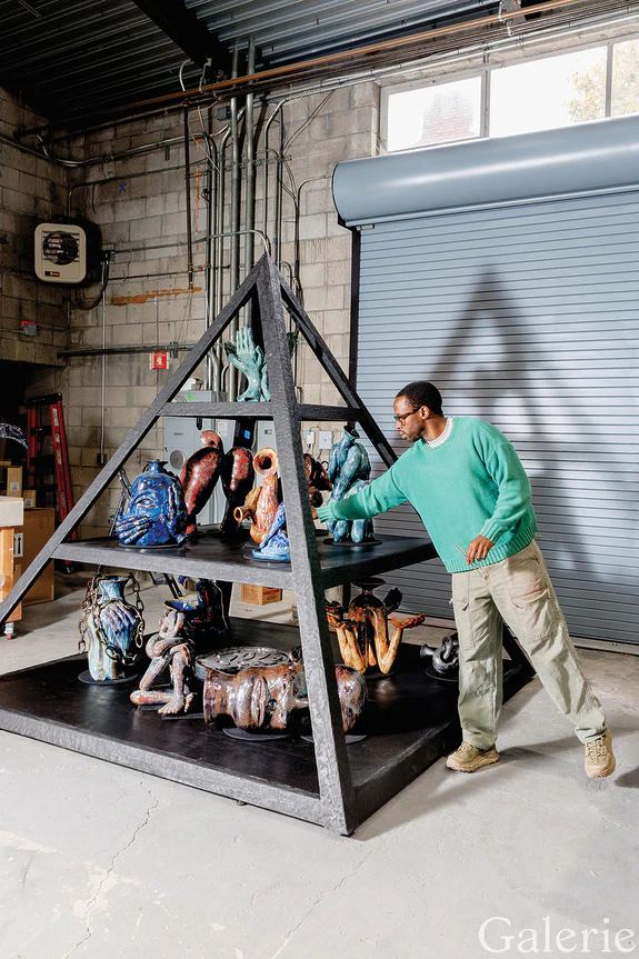 Person arranging colorful sculptures on a pyramid-shaped shelf in an industrial setting