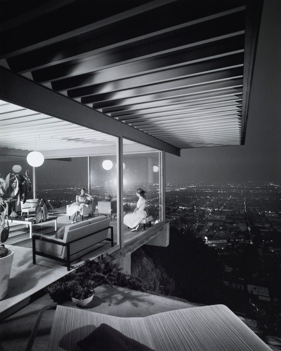 Modernist home overlooking a nighttime cityscape with figures inside.