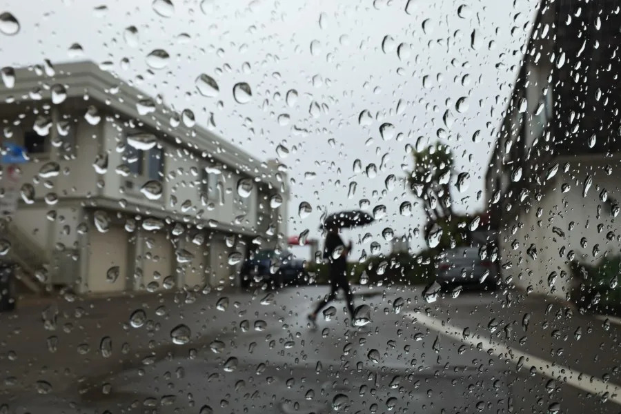 Long Beach, CA – November 14: Rain drops on a windshield frame a person breaving the elements in Sunset Beach Friday, Nov. 14, 2025. Residents and businesses are bracing for stormy weather expected to soak much of the region Friday and into the weekend. (Allen J. Schaben / Los Angeles Times via Getty Images)