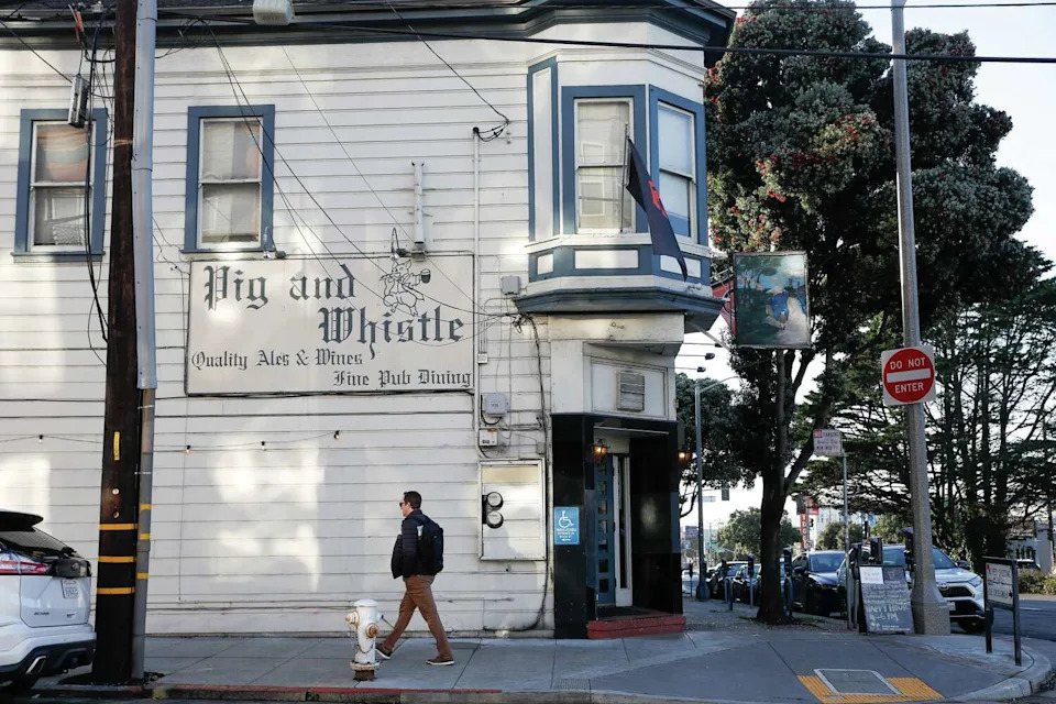 A pedestrian walks past The Pig and Whistle in San Francisco. The block on Geary Boulevard will soon change as a new high school athletic complex will be constructed. (Lea Suzuki/S.F. Chronicle)