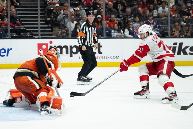 Detroit Red Wings center Dylan Larkin, right, shoots as Ducks...