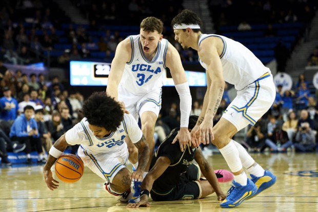 UCLA guard Skyy Clark, left, dives for the ball against...