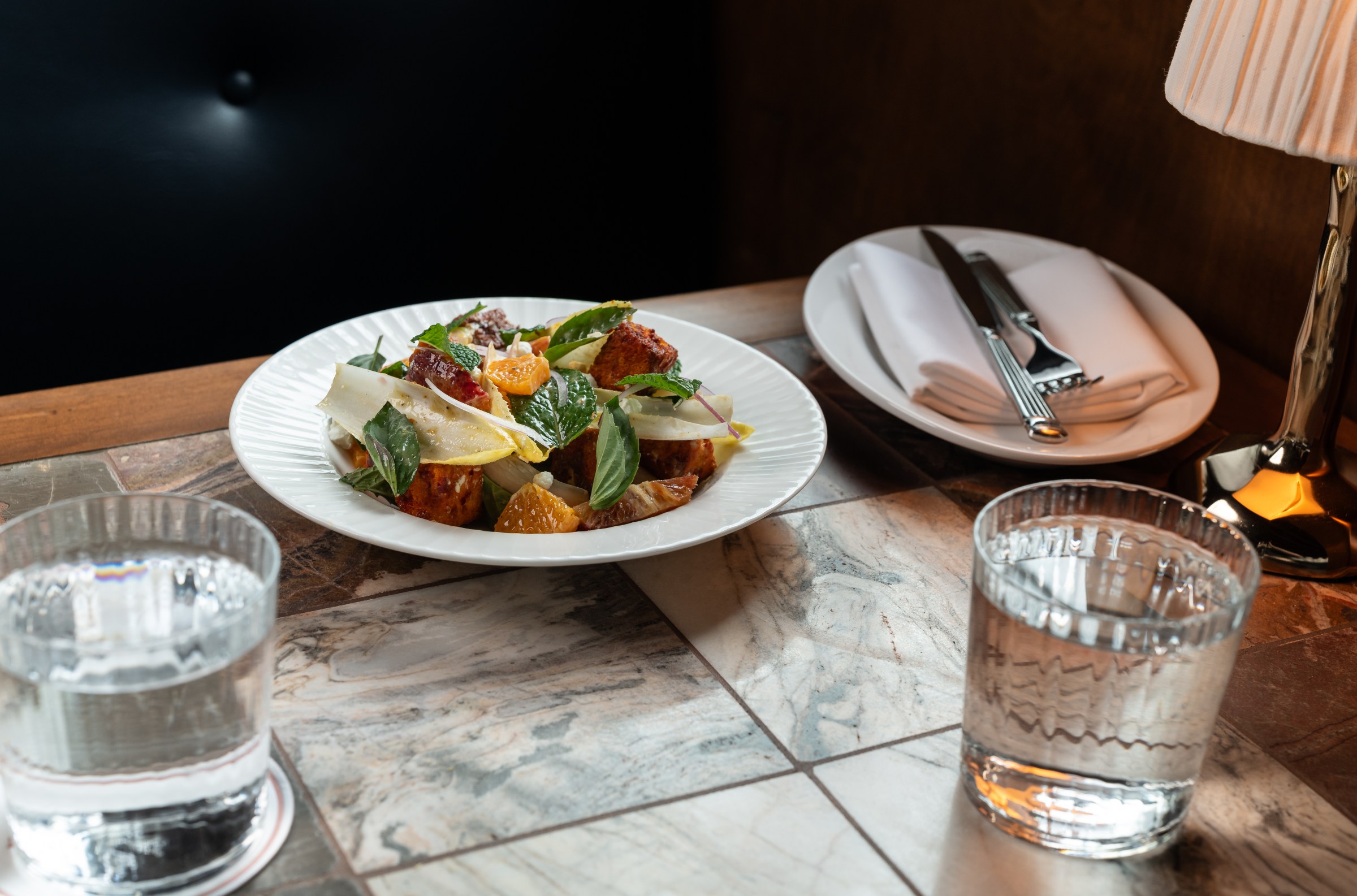 Citrus panzanella in a shallow white bowl with croutons at Hermon’s