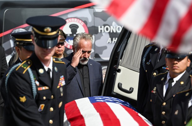 Jared Chandler, center, salutes hos son, U.S. Army PFC Jake...