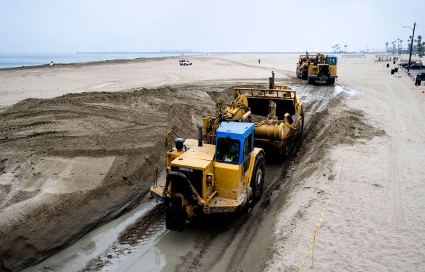 Heavy equipment moves sand that will create a berm in...