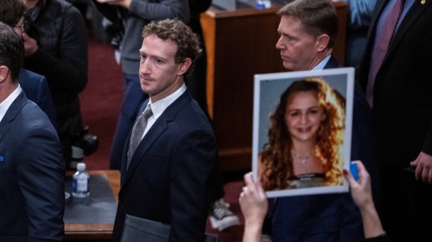 Mark Zuckerberg, CEO of Meta, walks past the photo of...