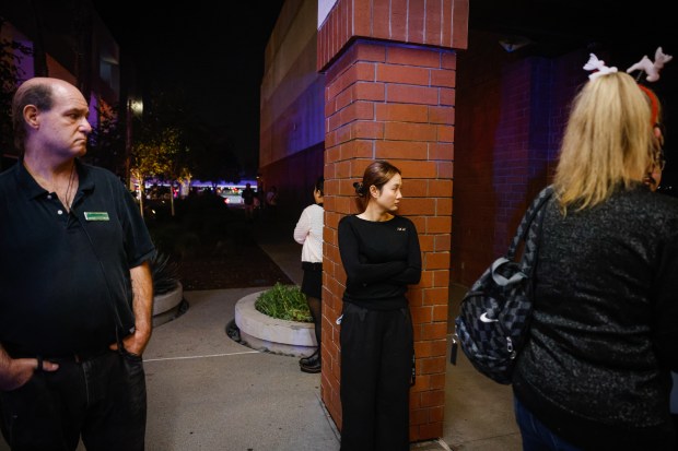 People wait for employees, friends, and family to be escorted...