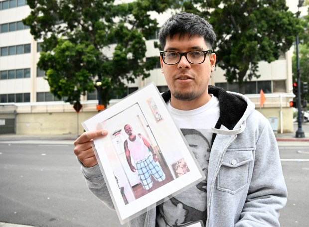 Justino Rupard, son of Lonnie Rupard, holds up photos of his father at a rally in front of the San Diego Central Jail on March 4, 2023. (Denis Poroy / For The San Diego Union-Tribune)
