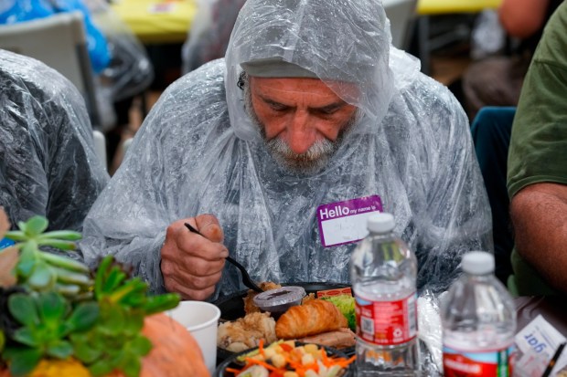 Still wearing his rain poncho, Clay Hall, 54, sat back and enjoyed a hot Thanksgiving meal at the annual Thanksgiving Dinner hosted by the San Diego Rescue Mission on Saturday.  (Nelvin C. Cepeda / The San Diego Union-Tribune)