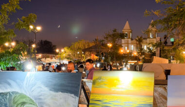 San Jose Del Cabo Art Walk at night with paintings in the foreground and church and moon in the background