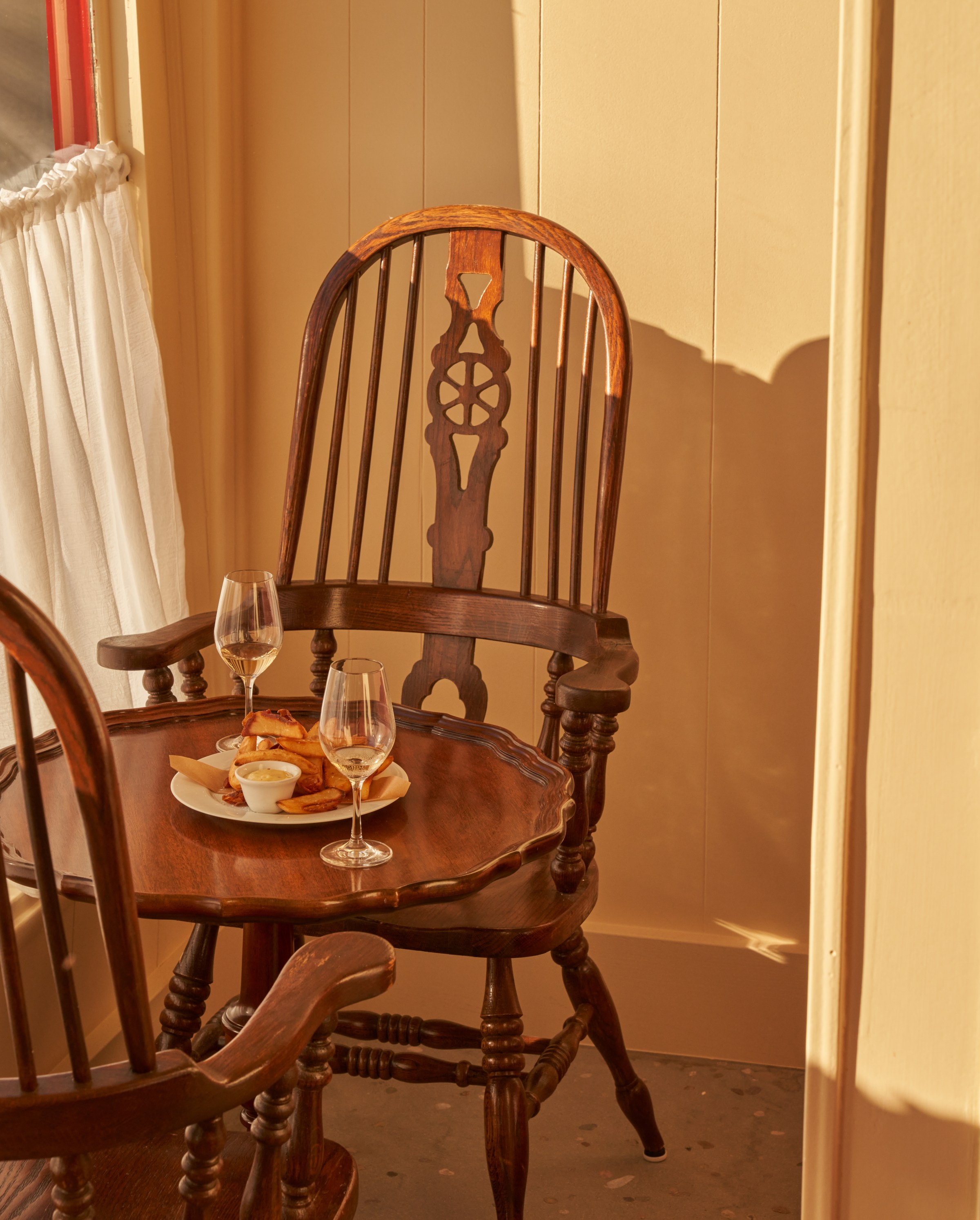 Table bathed in light with a plate of french fries at Wilde’s