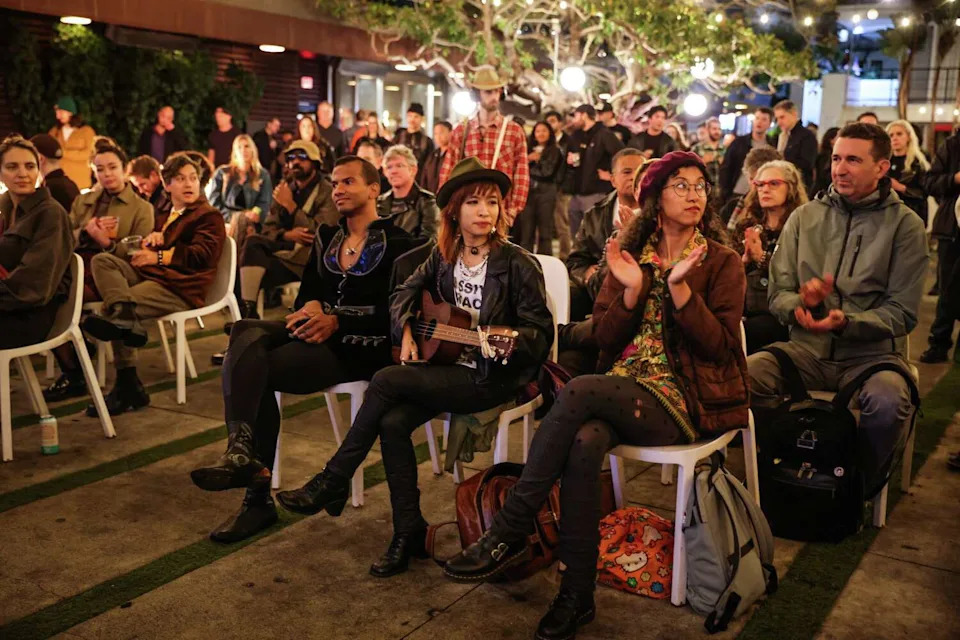 People gather to listen to a poetry reading at the Phoenix Hotel's farewell block party in San Francisco on Thursday, Nov. 13, 2025. (Gabrielle Lurie/S.F. Chronicle)
