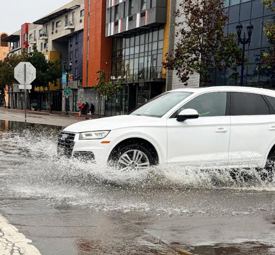 A sedan enters an intersection despite the wet conditions from a fall storm.