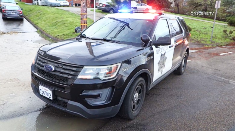A black and white law enforcement vehicle blocks an intersection