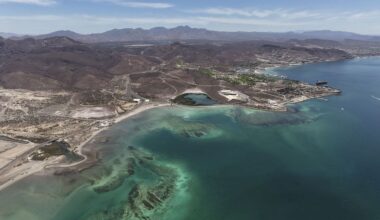 Aerial view of Mexico's rugged coastline with clear turquoise waters and arid mountain terrain in the background