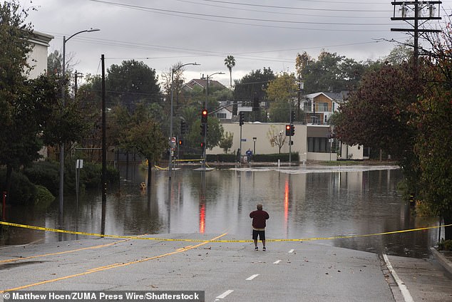 A man looks at a flooded intersection in the South Pasadena area of Los Angeles, as evacuation warnings forced many in burn areas to leave their homes