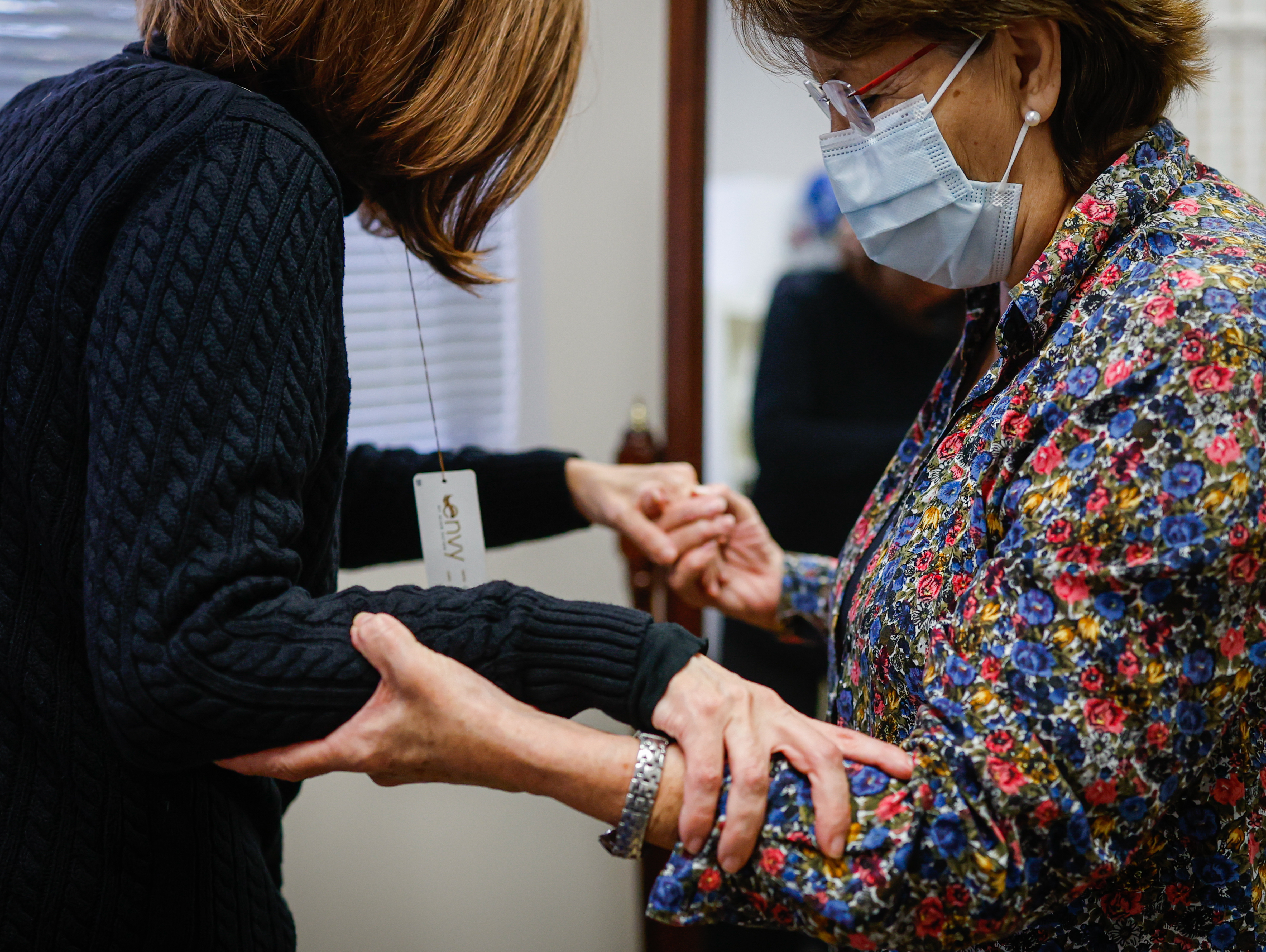 Gilma Pereda, of Santa Clara, left, receives help standing up...