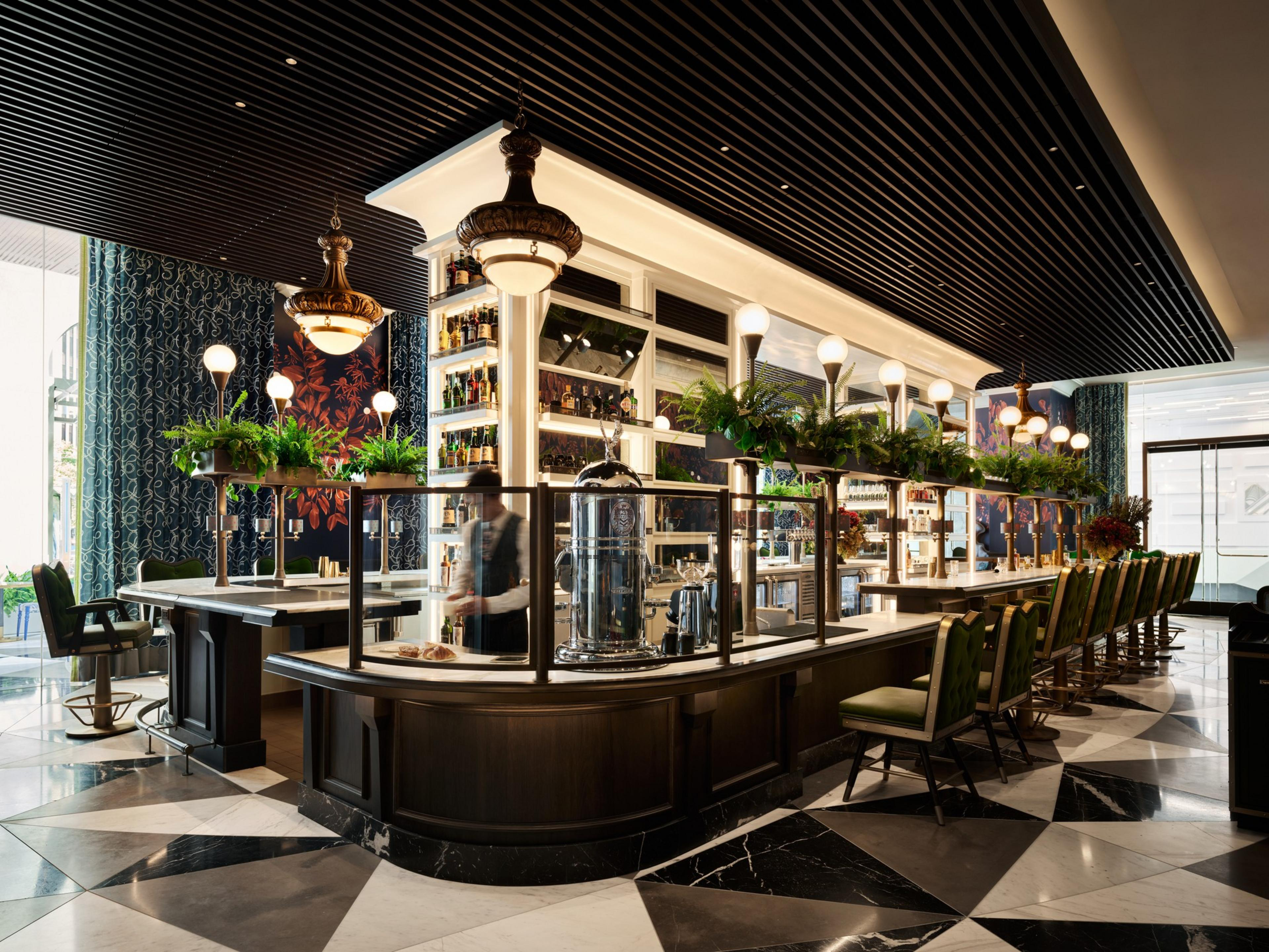 A fancy bar top with globe lights and glass windows has barber chair style seats alongside it.