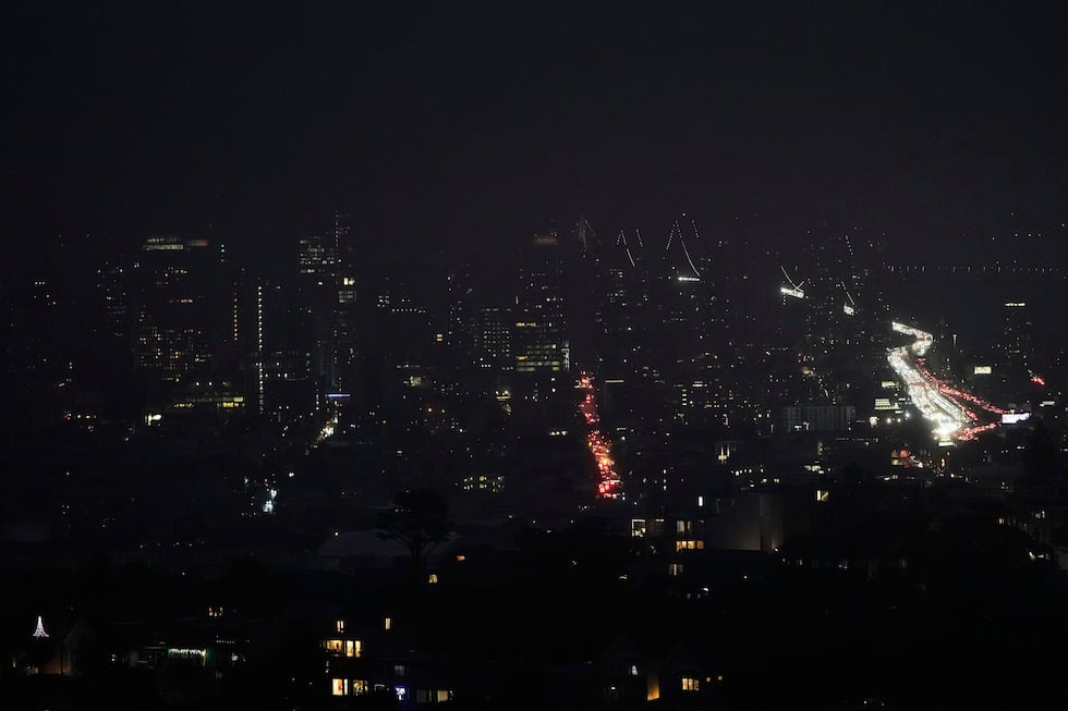 Fog and power outages darken the skyline as traffic moves in San Francisco, Saturday, Dec. 20,...
