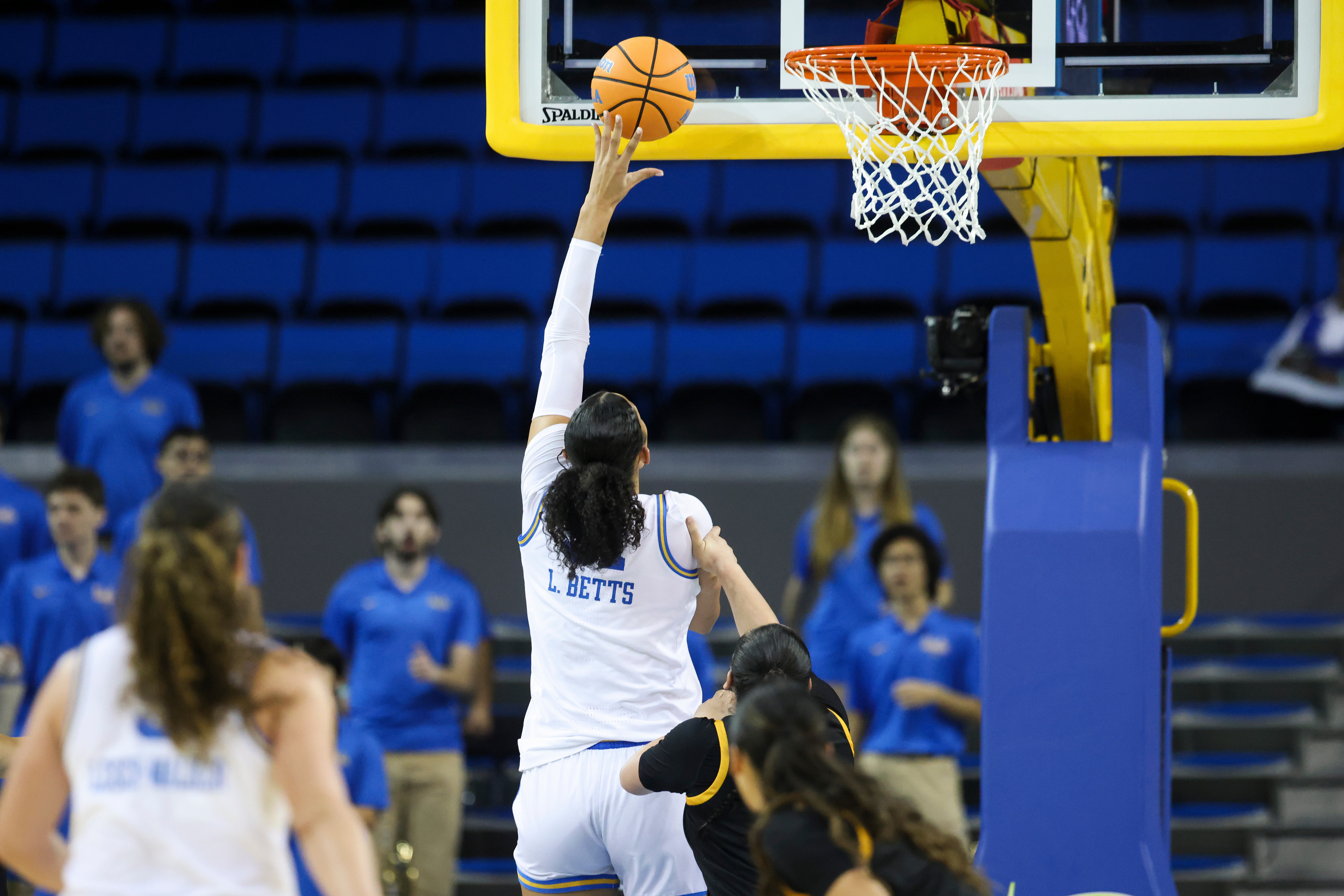 UCLA center Lauren Betts, center, shoots as guard Charlisse Leger-Walker,...