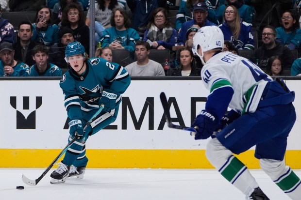 San Jose Sharks center Will Smith (2) moves the puck during the first period of an NHL hockey game against the Vancouver Canucks, Friday, Nov. 28, 2025, in San Jose, Calif. (AP Photo/Godofredo A. Vásquez)