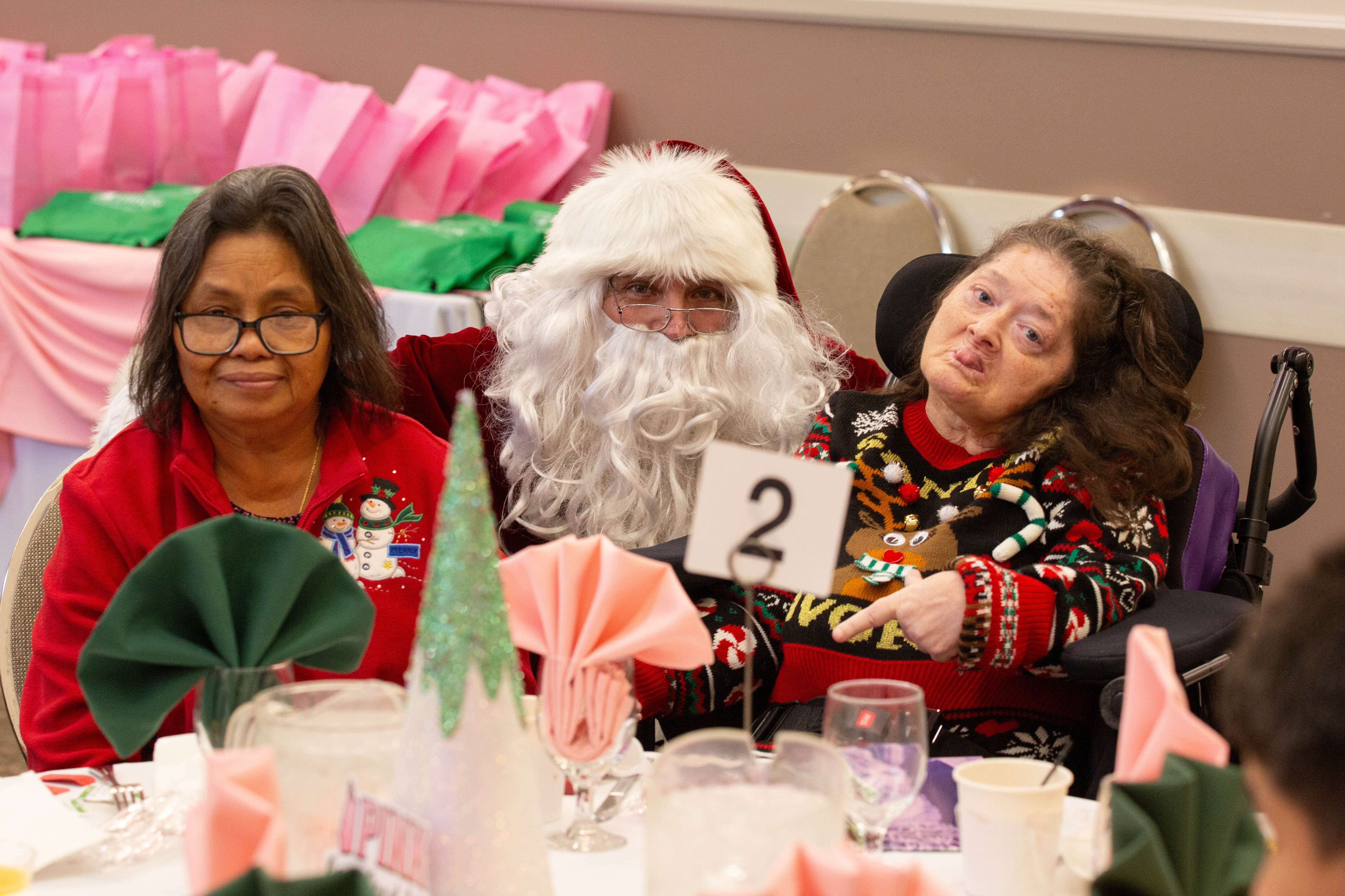 Santa Claus takes a photo with two attendees during the...