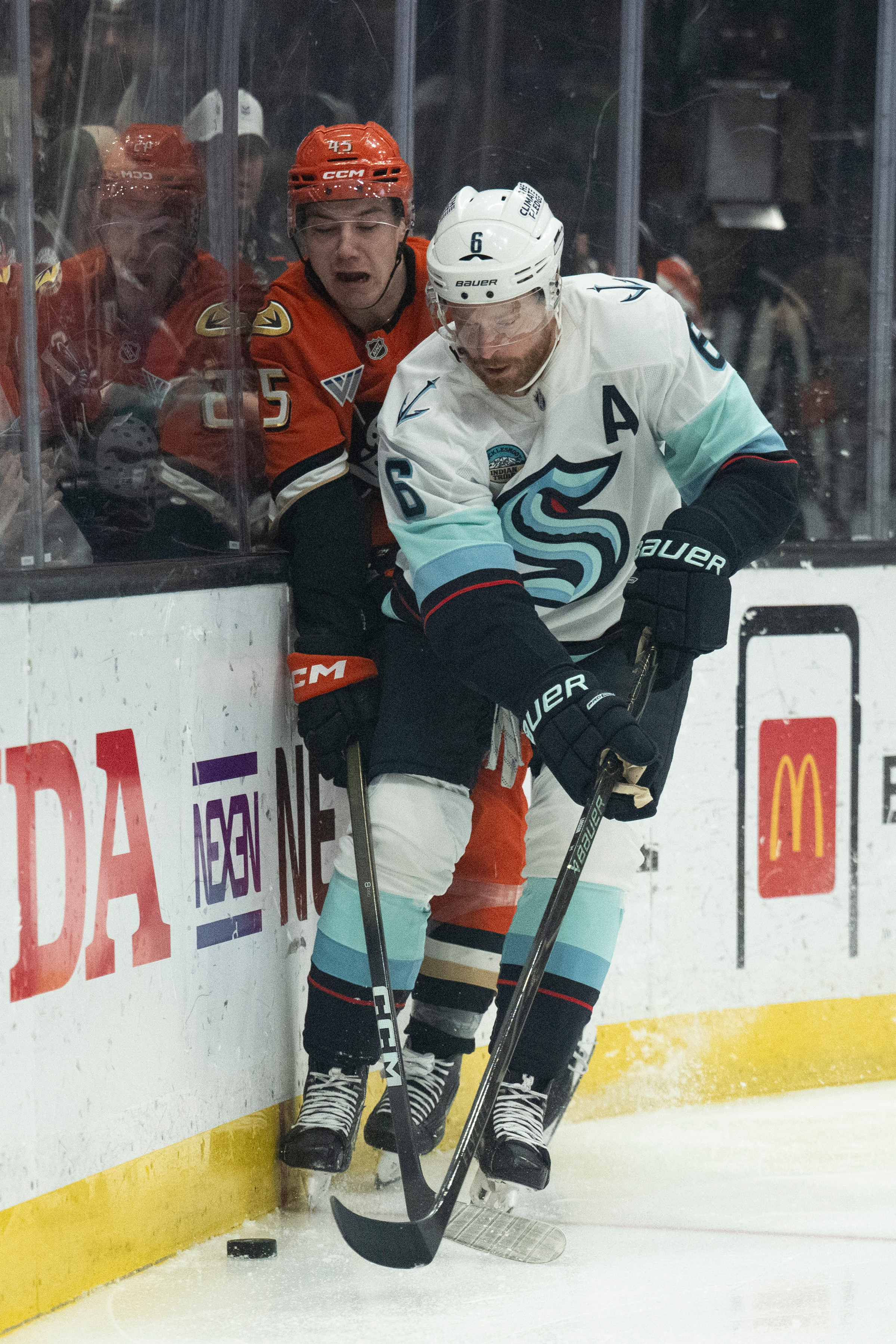 Seattle Kraken defenseman Adam Larsson, right, vies for the puck...