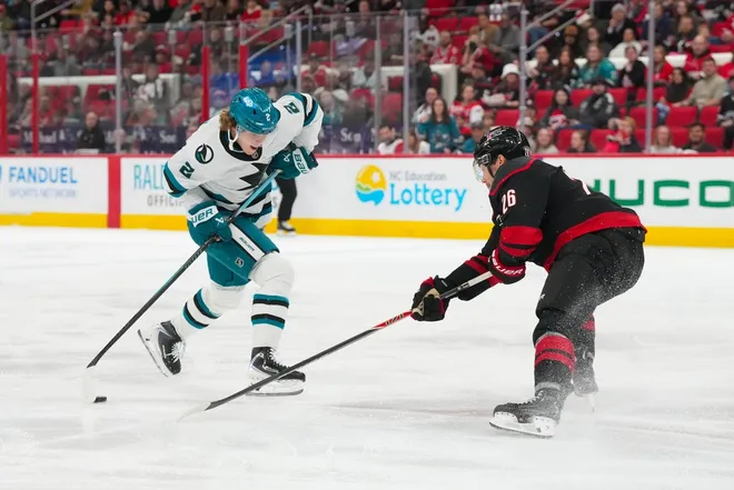 Dec 7, 2025; Raleigh, North Carolina, USA; San Jose Sharks center Will Smith (2) skates with the puck against Carolina Hurricanes defenseman Sean Walker (26) during the second period at Lenovo Center.