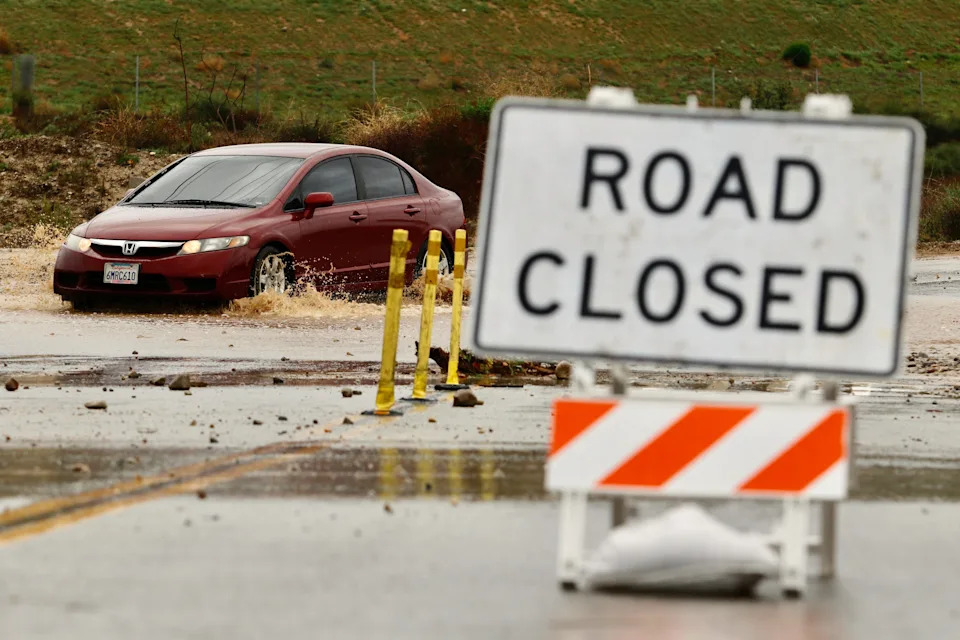 A driver goes though a road closed for flooding, Wednesday, Dec. 24, 2025, in in Valencia, Calif.