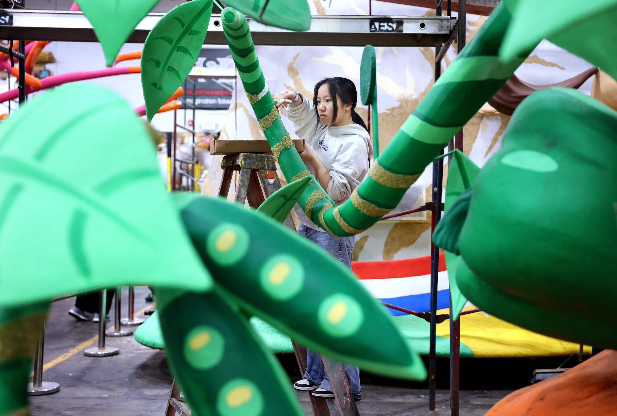 Volunteer Heather Tran, 16, helps decorate a float for the Rose Parade at the AES Rosamont Pavillion in Pasadena.