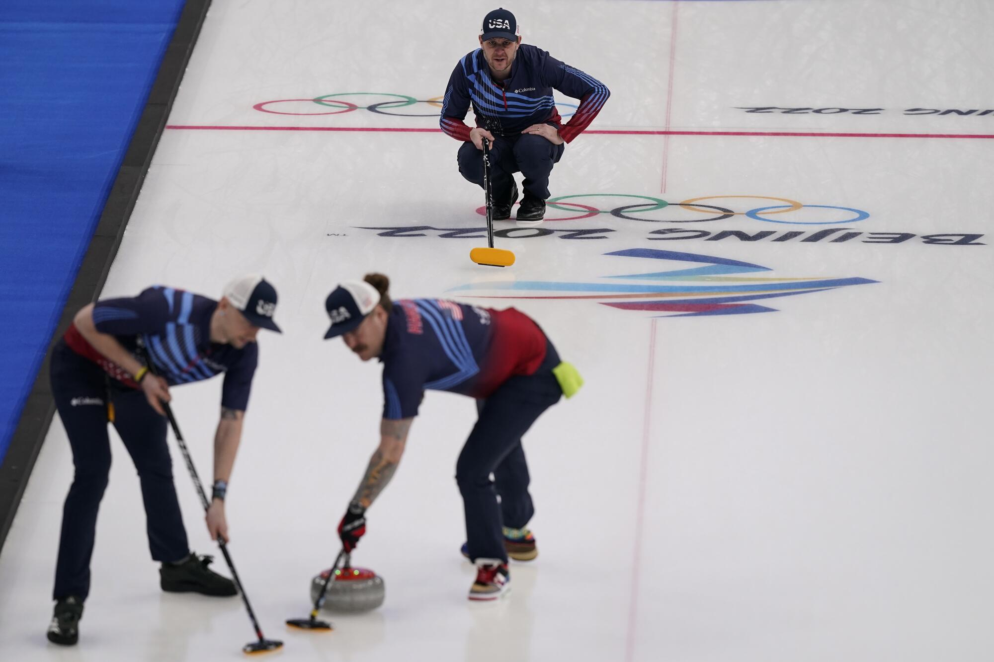 American John Shuster watches Matt Hamilton and Colin Hufman sweep his throw during a 2022 Olympics match.