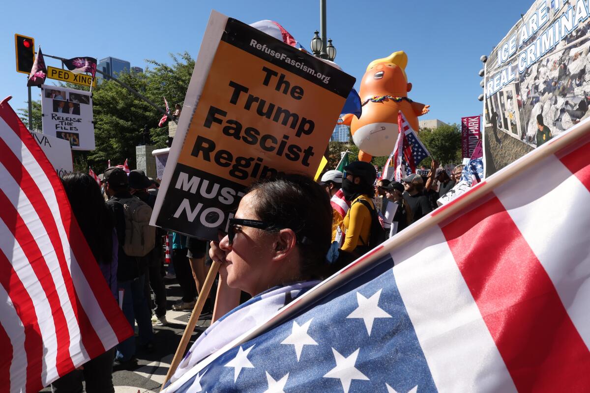 A woman standing before an American flag during an anti-Trump protest in downtown Los Angeles.