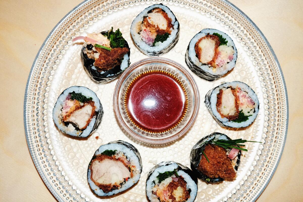 Sliced fried chicken kimbap on a glass plate with dipping sauce at Super Peach