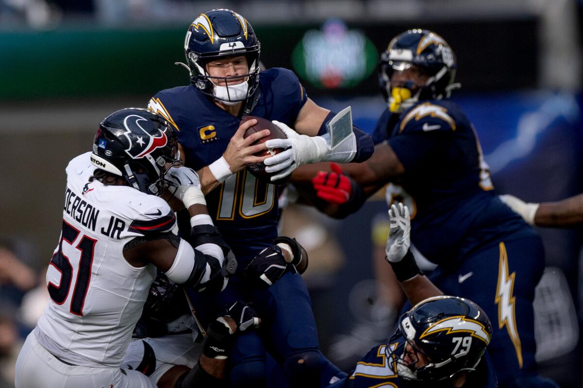 Chargers quarterback Justin Herbert is sacked by Texans' Will Anderson Jr. and Sheldon Rankins.