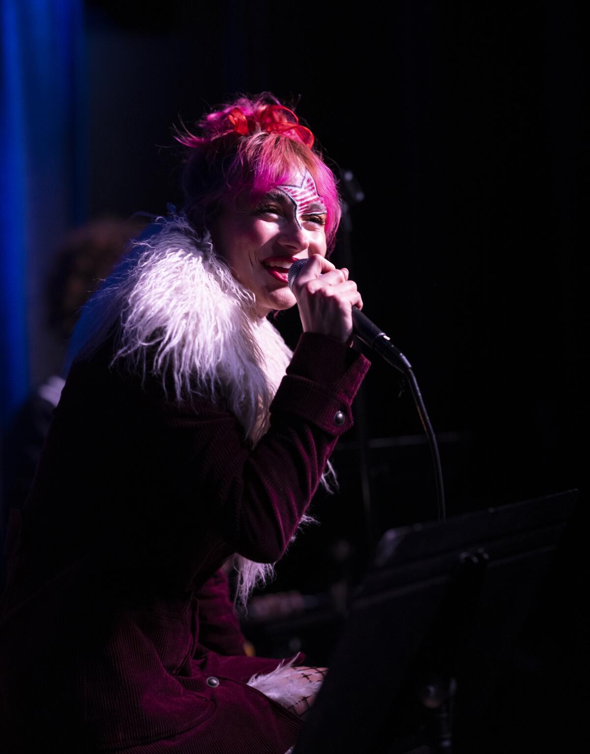 Maris, with pink hair, sings into a microphone.