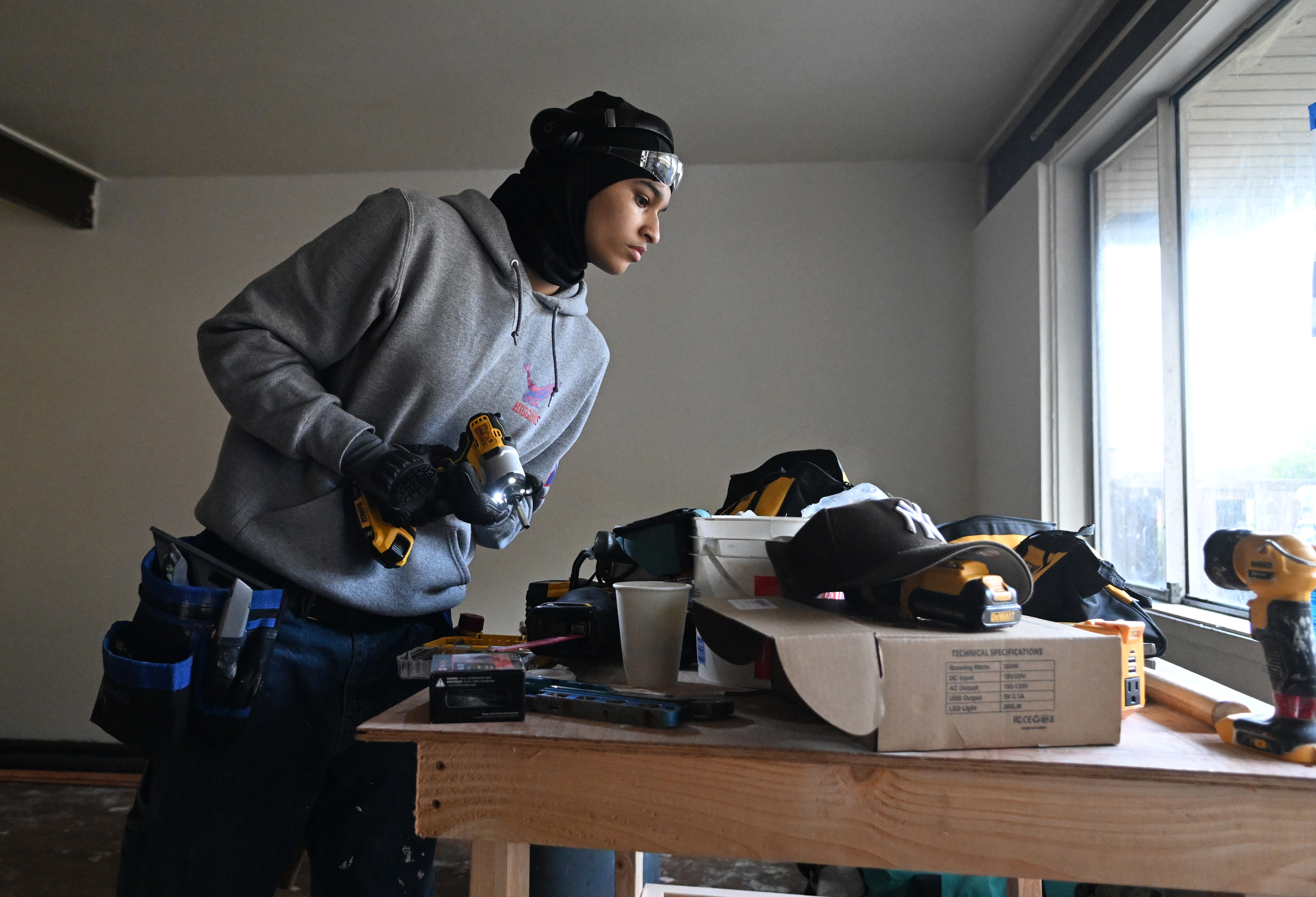 Trainee Sanaa Green grabs tools off a table in an...