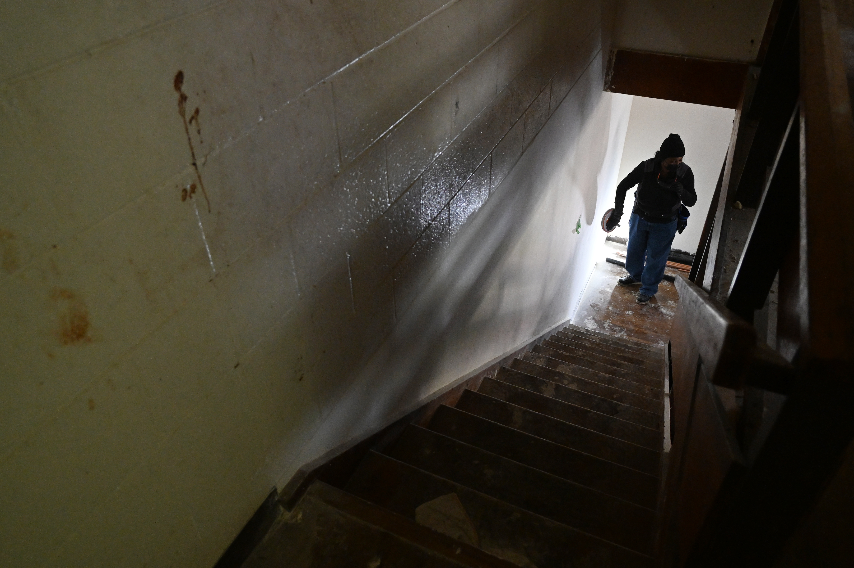 Trainee Hershey Cherry sands a wall in an apartment being...