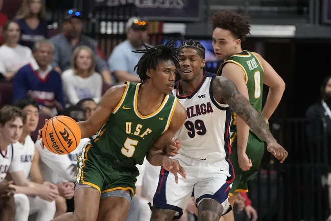 March 10, 2025; Las Vegas, NV, USA; San Francisco Dons guard Tyrone Riley IV (5) dribbles the basketball against Gonzaga Bulldogs guard Khalif Battle (99) during the first half in the semifinal of the West Coast Conference tournament at Orleans Arena.