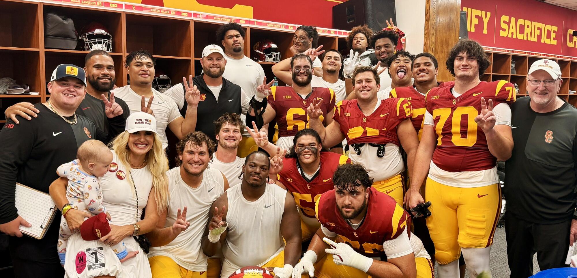 USC offensive line coach Zach Hanson; his wife, Annie; and son, Rock, join linemen and staff for a group photo.